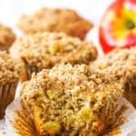 An unwrapped apple streusel muffin with a large bite taken out of it