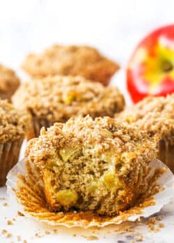 An unwrapped apple streusel muffin with a large bite taken out of it
