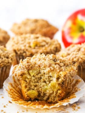 An unwrapped apple streusel muffin with a large bite taken out of it