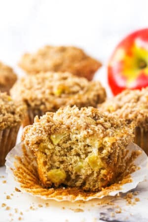 An unwrapped apple streusel muffin with a large bite taken out of it