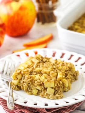 One portion of baked oatmeal on a plate with the remaining oatmeal bake in the background