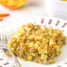A square of apple cinnamon baked oatmeal on a white plate on top of a red and white striped dishtowel