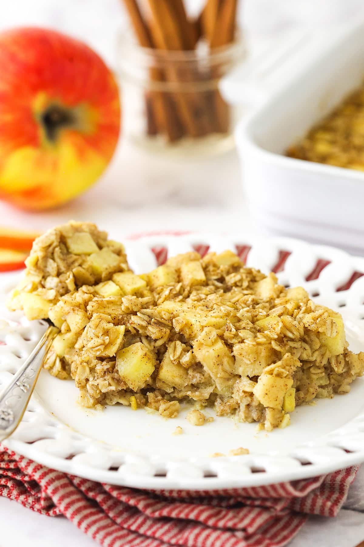 A slice of baked oatmeal on a plate with one bite on a metal spoon