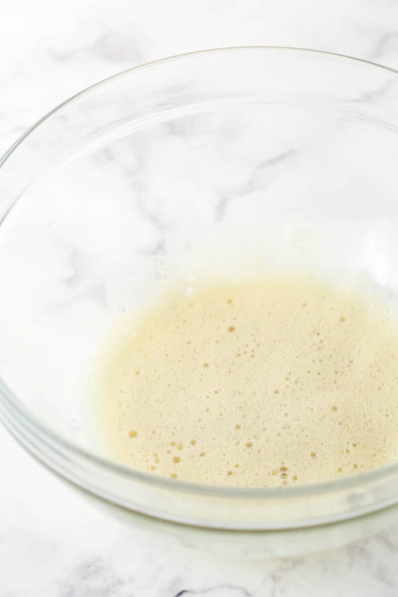 The whipped egg white and vanilla extract in a clear bowl.