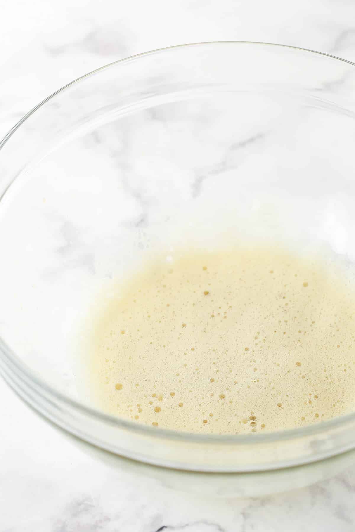 The whipped egg white and vanilla extract in a clear bowl