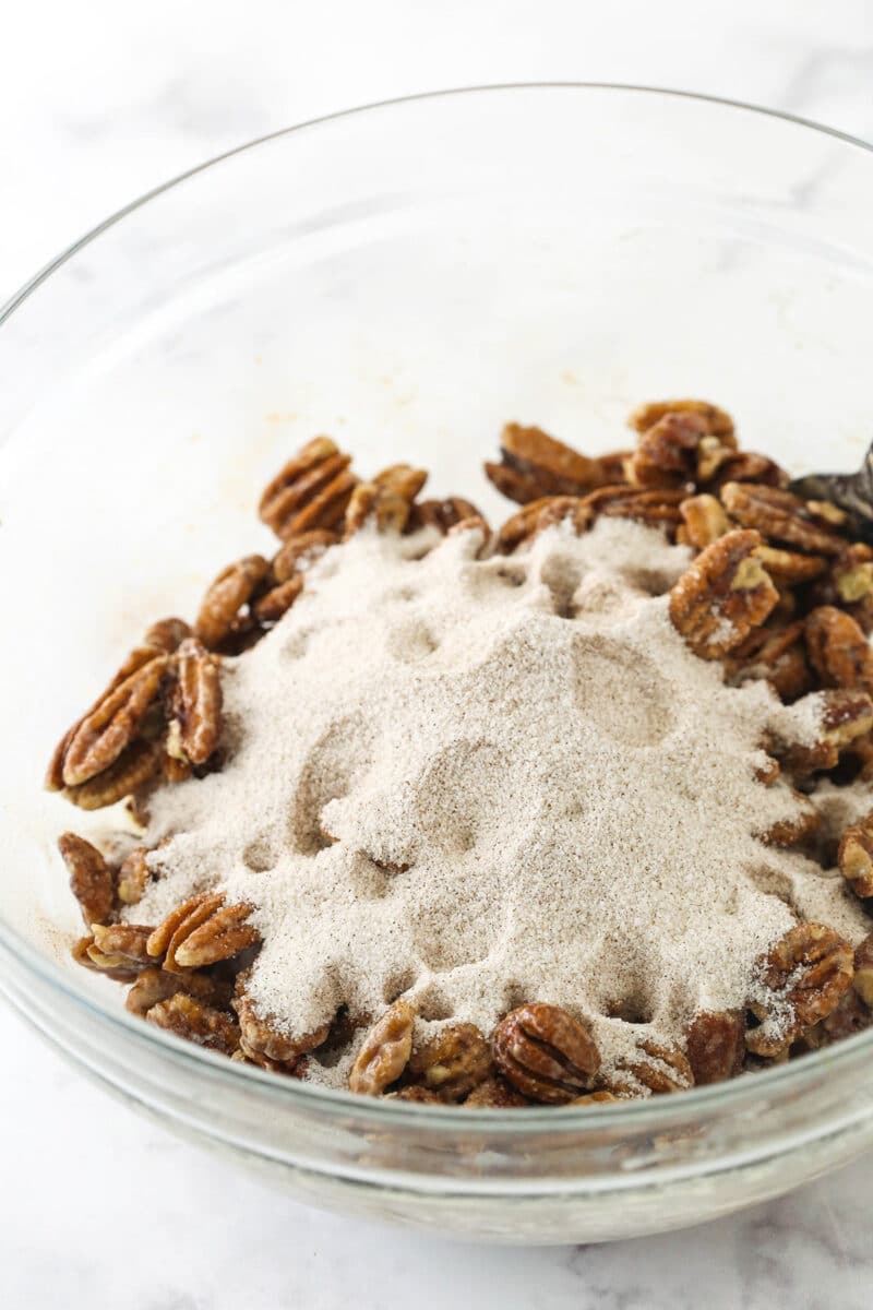 A bowl of pecans coated in whipped egg whites with cinnamon sugar poured on top.