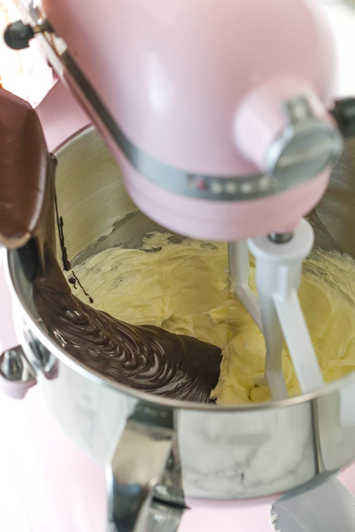 melted chocolate being added to butter for buttercream in mixing bowl on stand mixer
