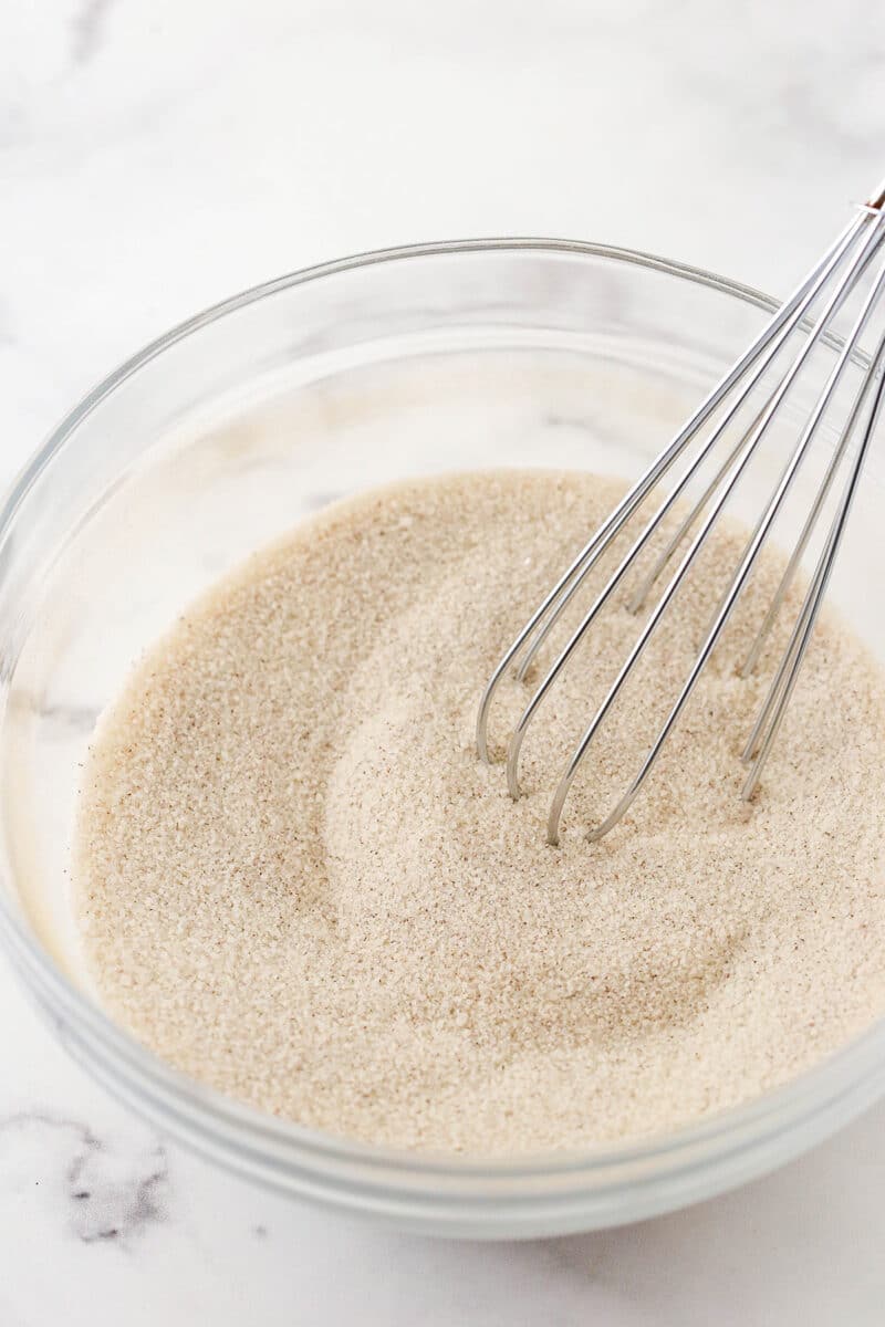 The cinnamon sugar mixture being whisked in a glass mixing bowl.