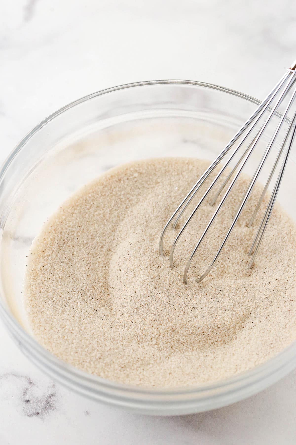 The cinnamon sugar mixture being whisked in a glass mixing bowl