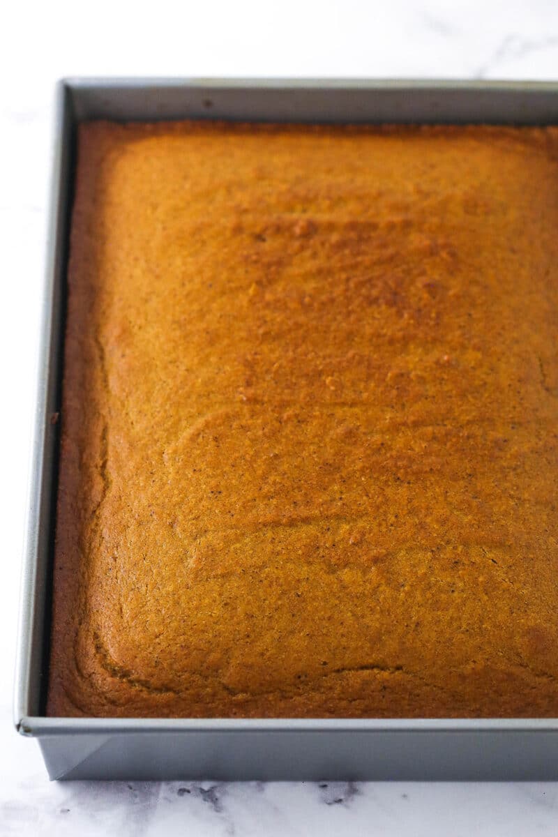 Cooled cake in a rectangular 9x13-inch pan on a marble surface