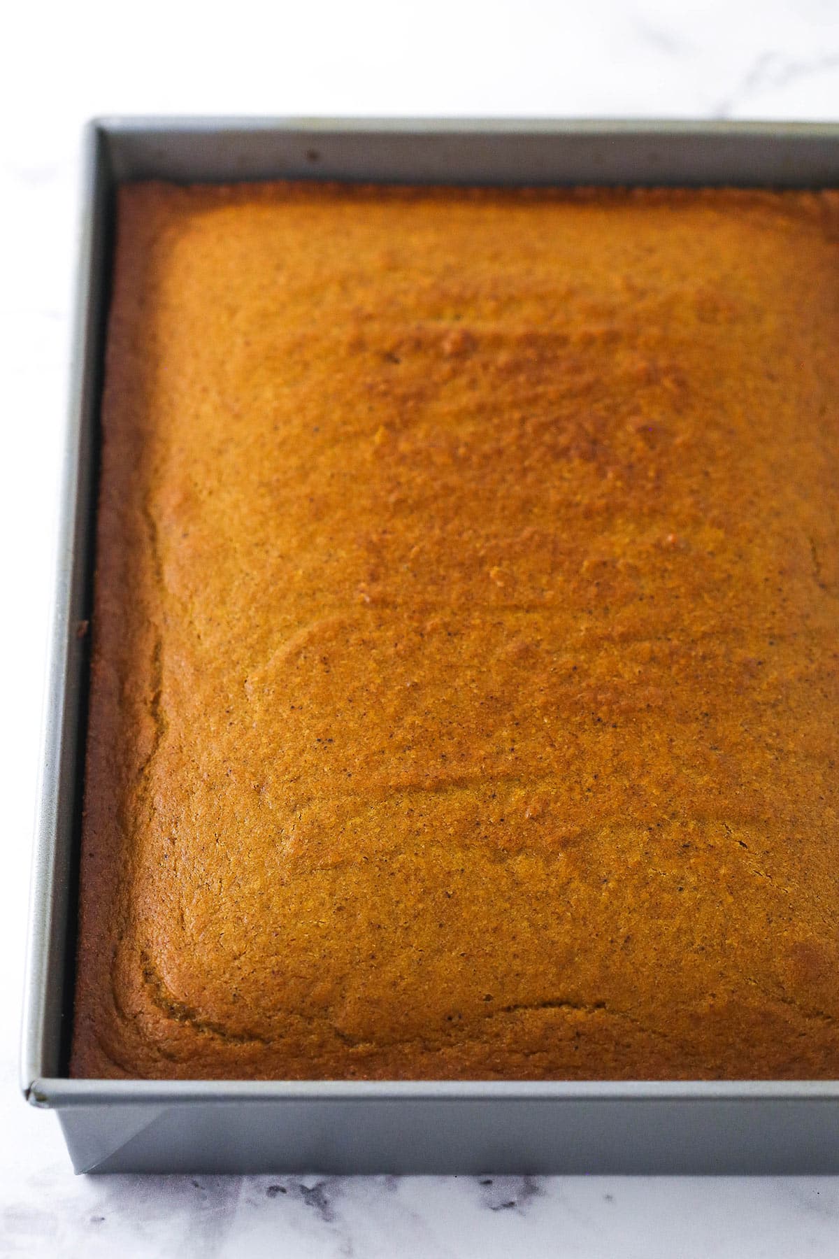 The cooled cake in a rectangular 9x13-inch pan on a marble surface