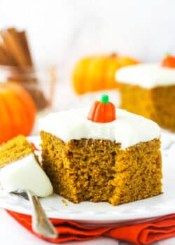 A piece of pumpkin cake on a plate with one bite on a metal dessert fork