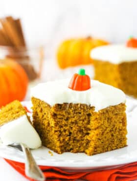 A piece of pumpkin cake on a plate with one bite on a metal dessert fork