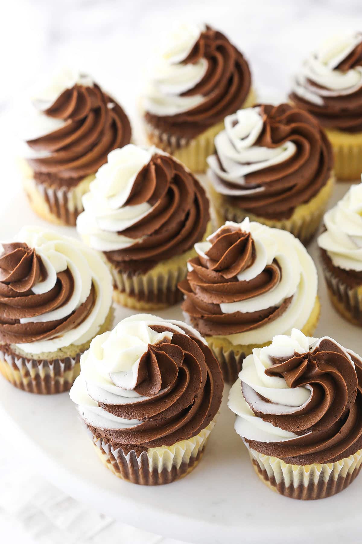 Frosted marble cupcakes on the round white platform of a cake stand