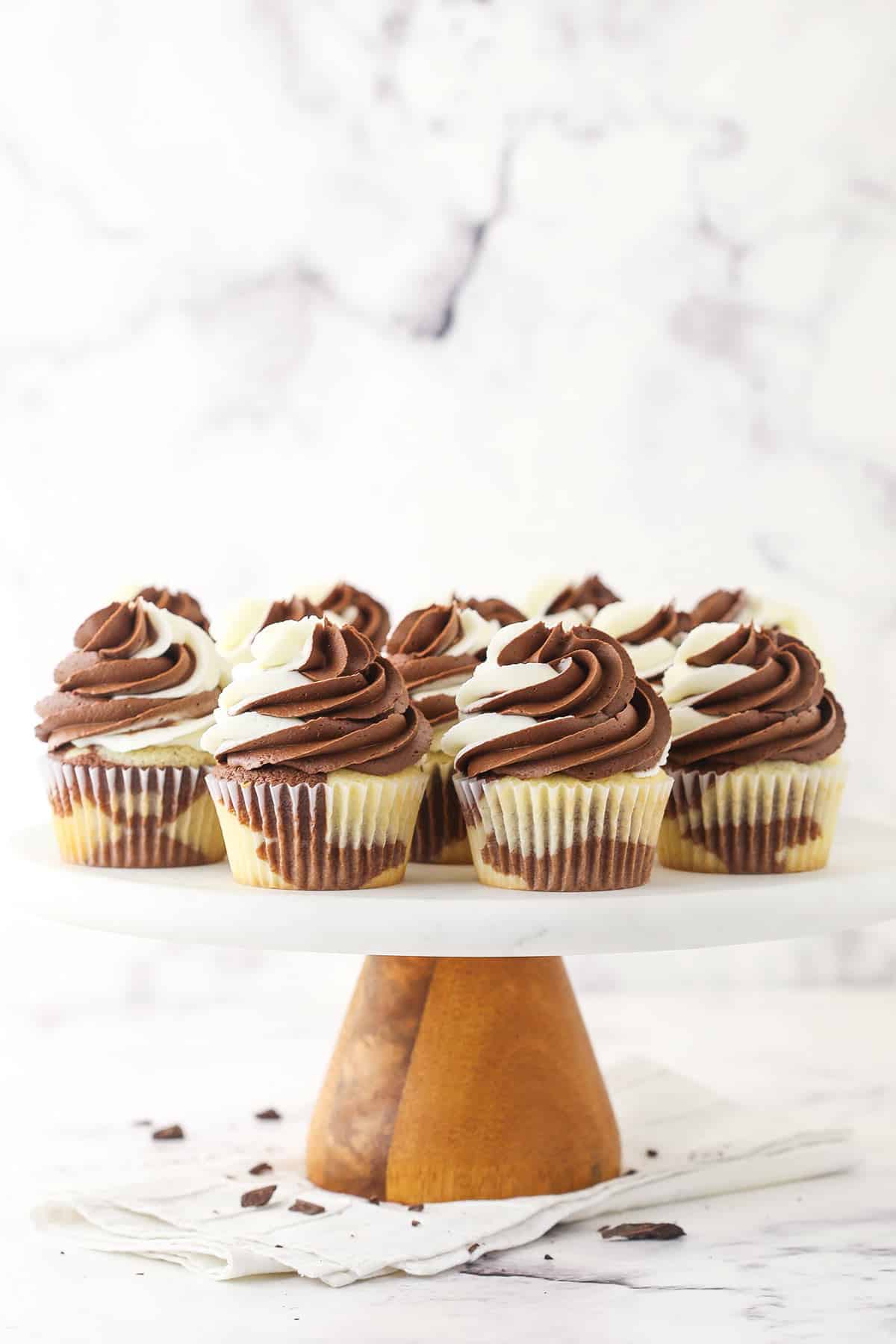 A tall cake stand holding a batch of vanilla and chocolate cupcakes