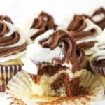 A marble cupcake on a cake stand with the wrapper peeled off and one bite taken out of it