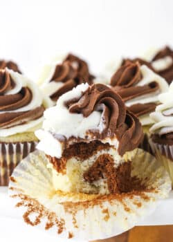 A marble cupcake on a cake stand with the wrapper peeled off and one bite taken out of it