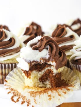 A marble cupcake on a cake stand with the wrapper peeled off and one bite taken out of it