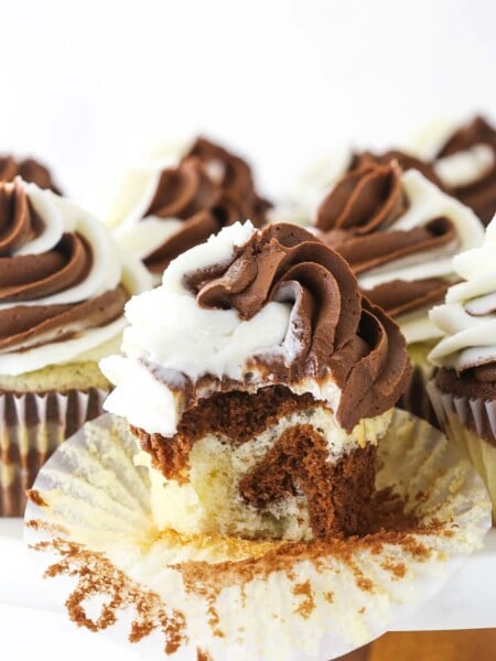 A marble cupcake on a cake stand with the wrapper peeled off and one bite taken out of it
