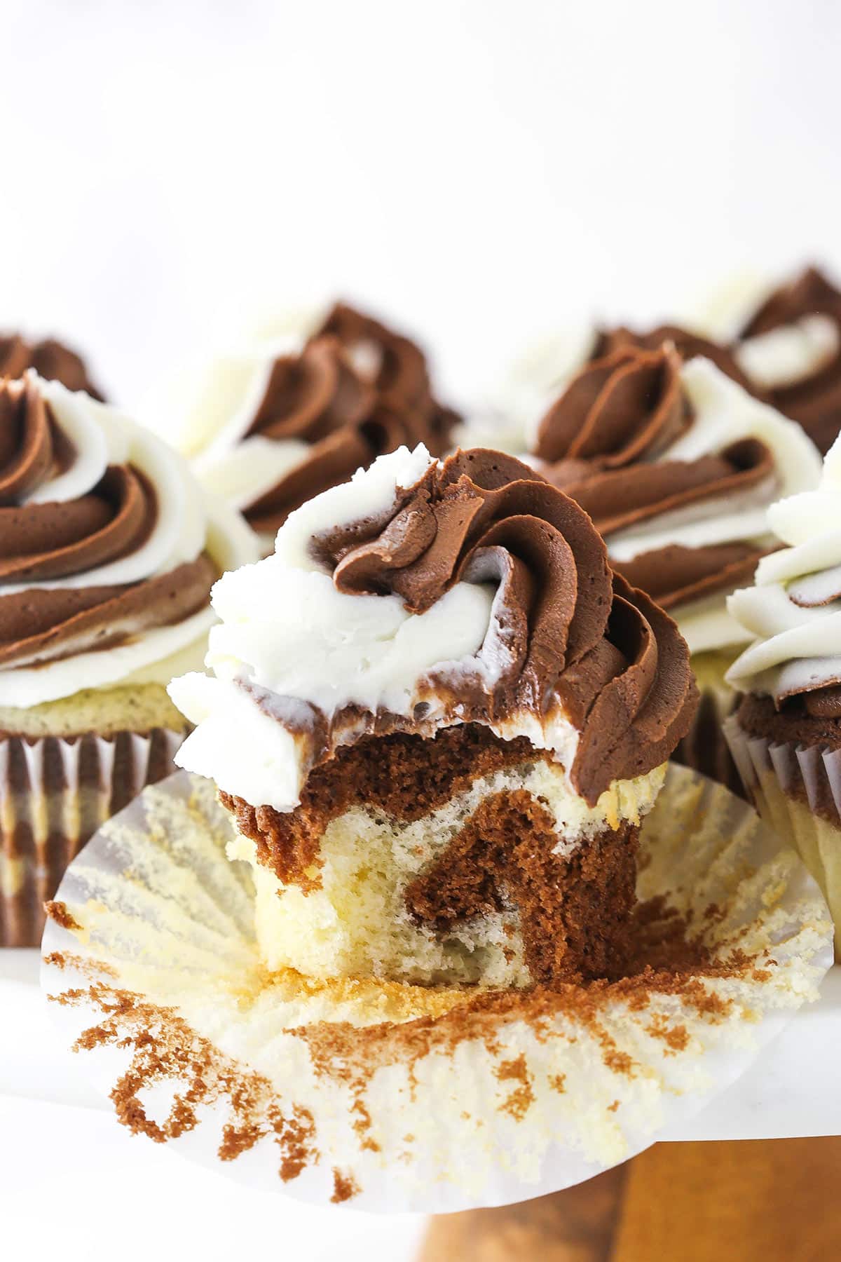 A marble cupcake on a cake stand with the wrapper peeled off and one bite taken out of it