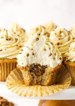 An unwrapped pecan pie cupcake with a bite taken out of it to reveal the gooey filling