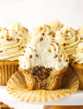 An unwrapped pecan pie cupcake with a bite taken out of it to reveal the gooey filling