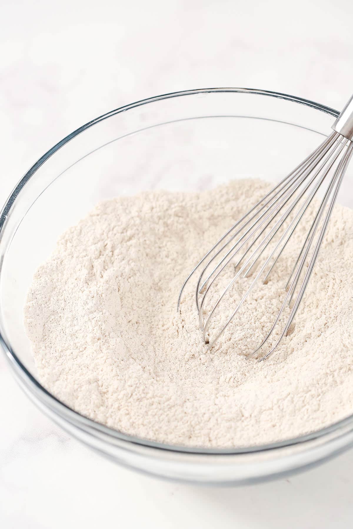 The combined dry ingredients in a mixing bowl with a metal whisk