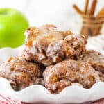 A white serving platter holding a pile of homemade apple fritters