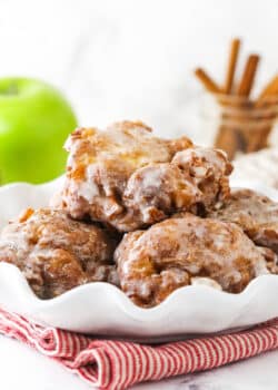 A white serving platter holding a pile of homemade apple fritters
