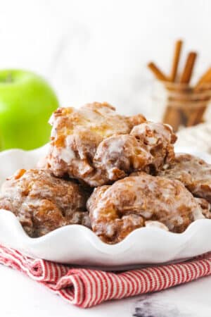 A white serving platter holding a pile of homemade apple fritters