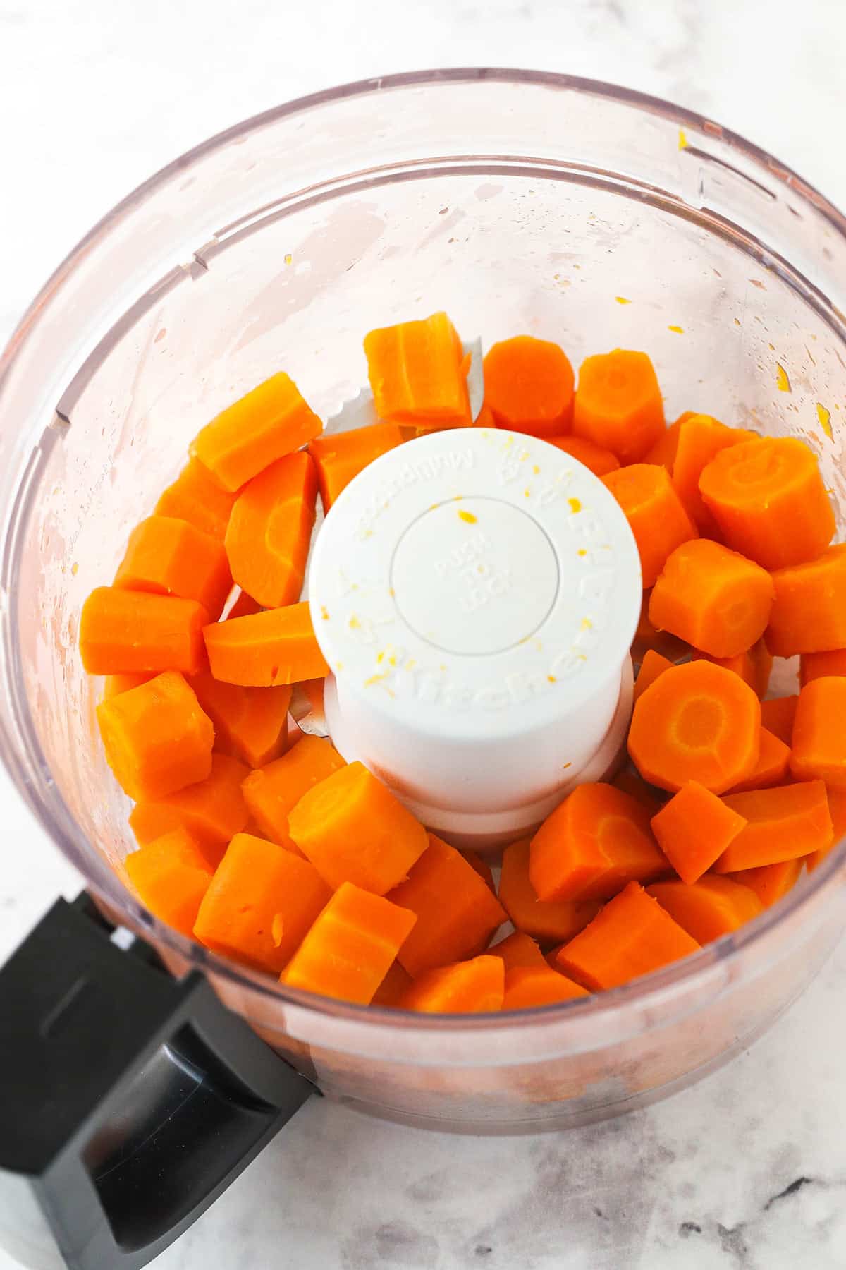 Sliced carrots inside of a large food processor