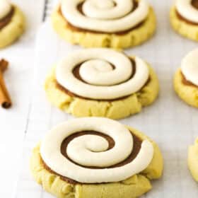 Filled and frosted cinnamon roll cookies lined up on a grid-patterned rack