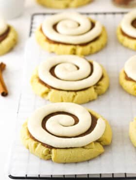 Filled and frosted cinnamon roll cookies lined up on a grid-patterned rack