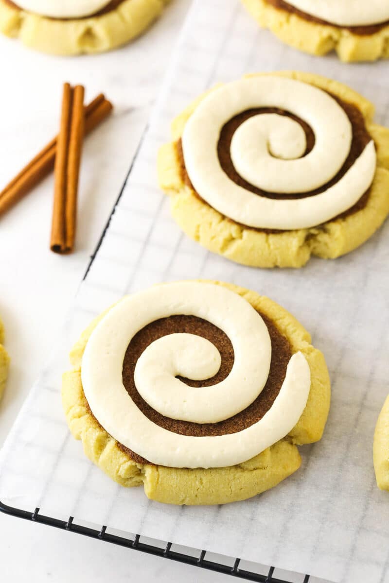 Copycat Crumbl cinnamon roll cookies lined up on a parchment-lined cooling rack