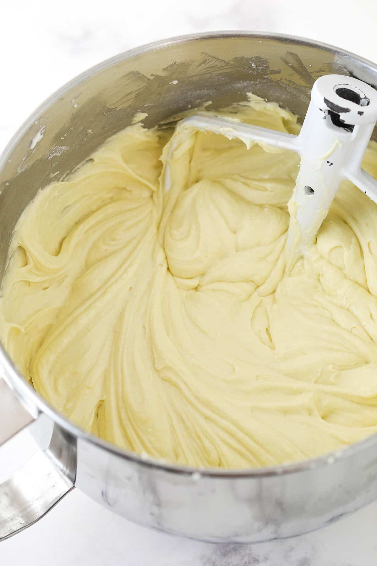 The completed bundt cake batter inside of a metal mixing bowl