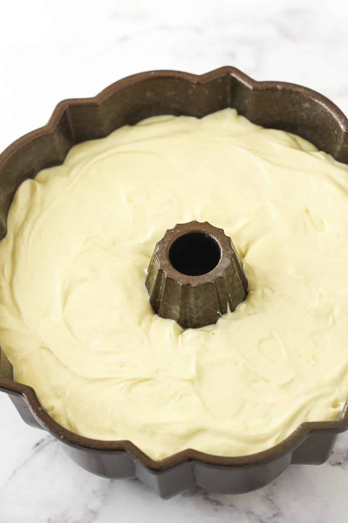 A fancy bundt pan containing cream cheese pound cake batter