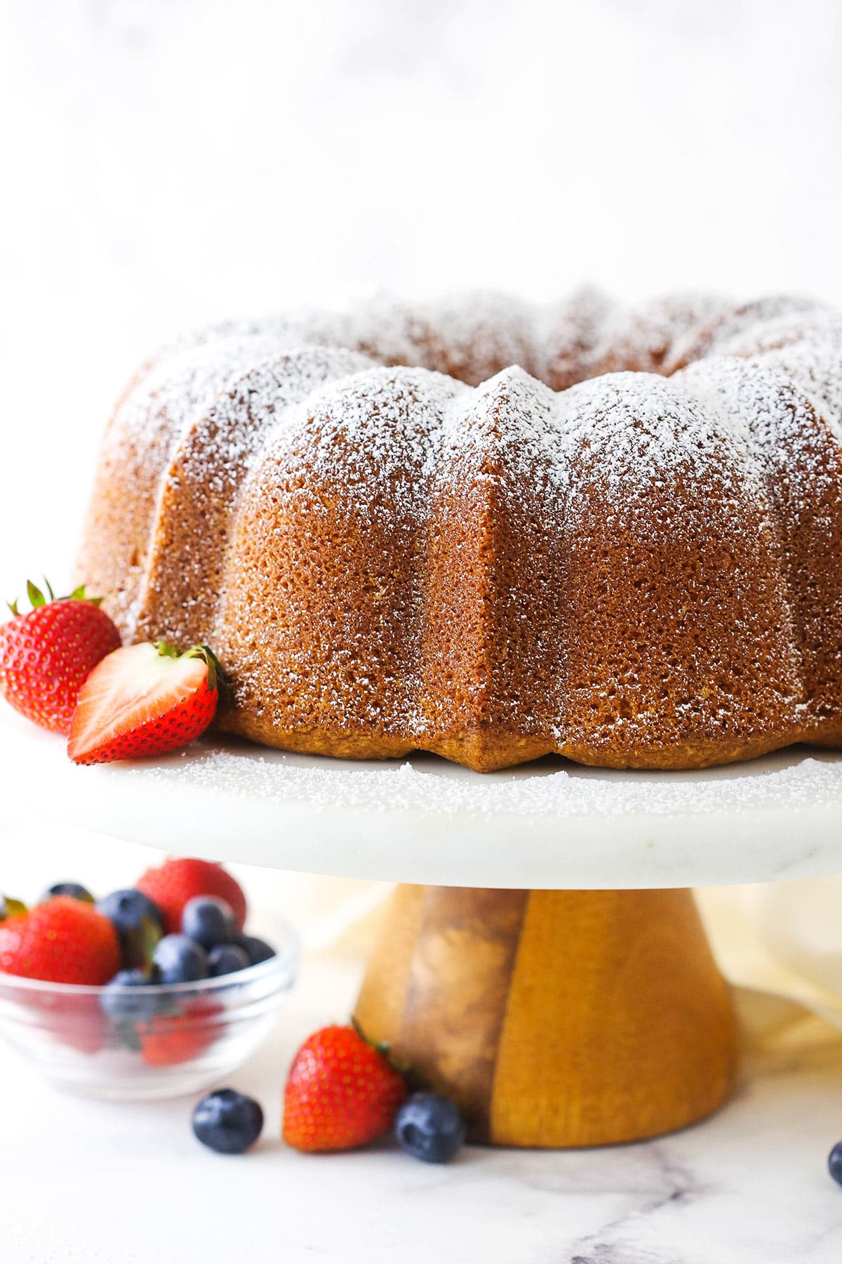A bundt cake on a cake stand with a dusting of powdered sugar on top
