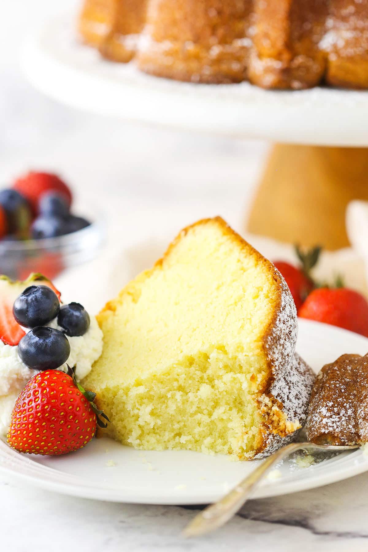 A piece of cream cheese pound cake on a plate with one bite on a fork