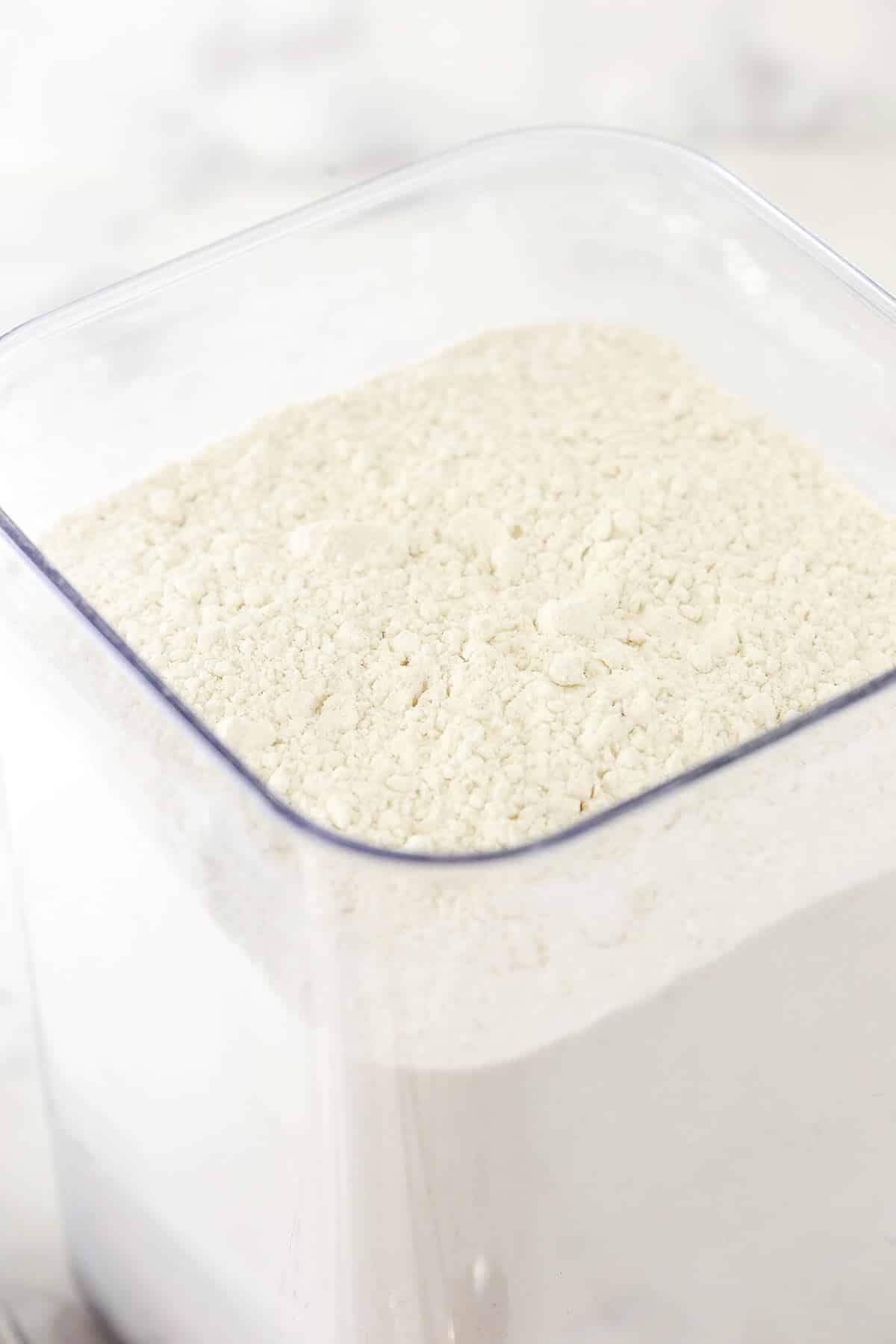 A close-up shot of a tall container full of all-purpose flour