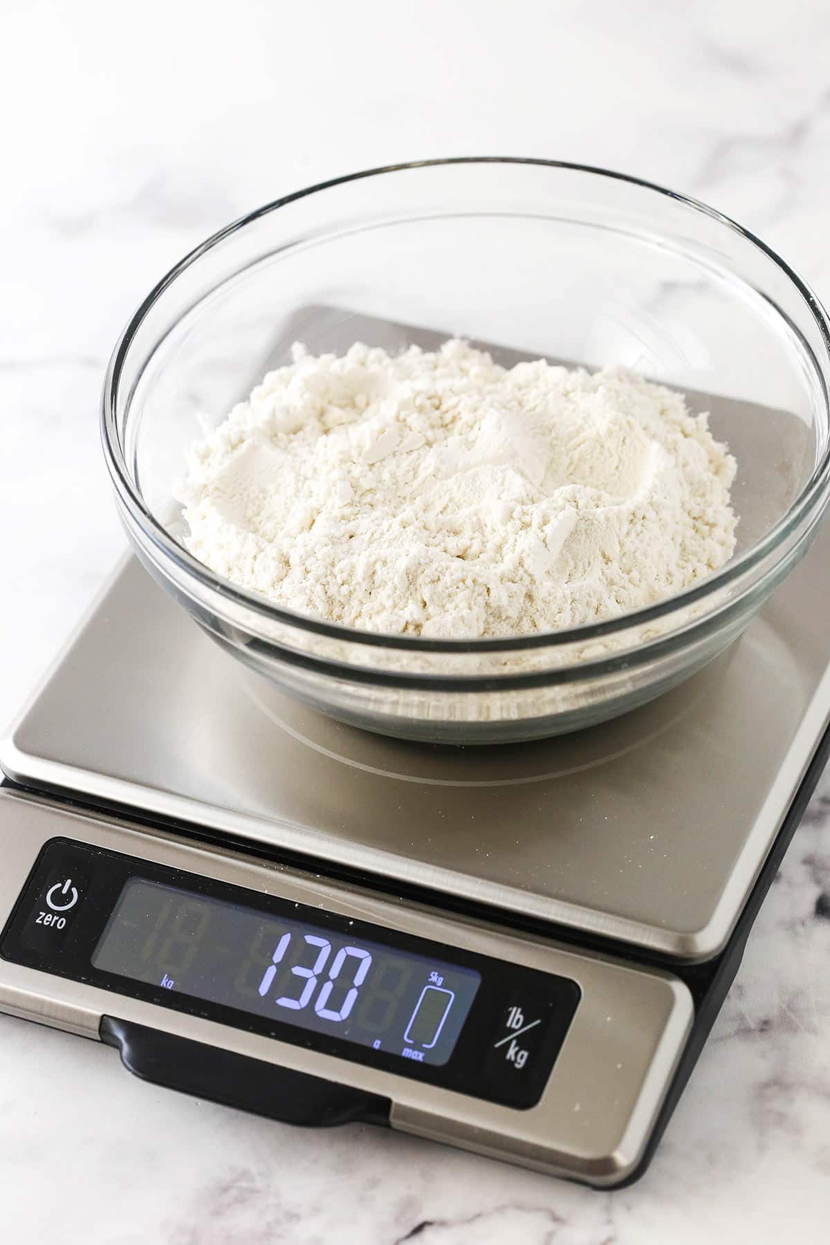 One cup of flour on a kitchen scale that reads 130 grams on the screen