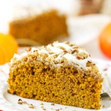 A slice of pumpkin coffee cake on a plate with a second slice and a jar of cinnamon sticks in the background
