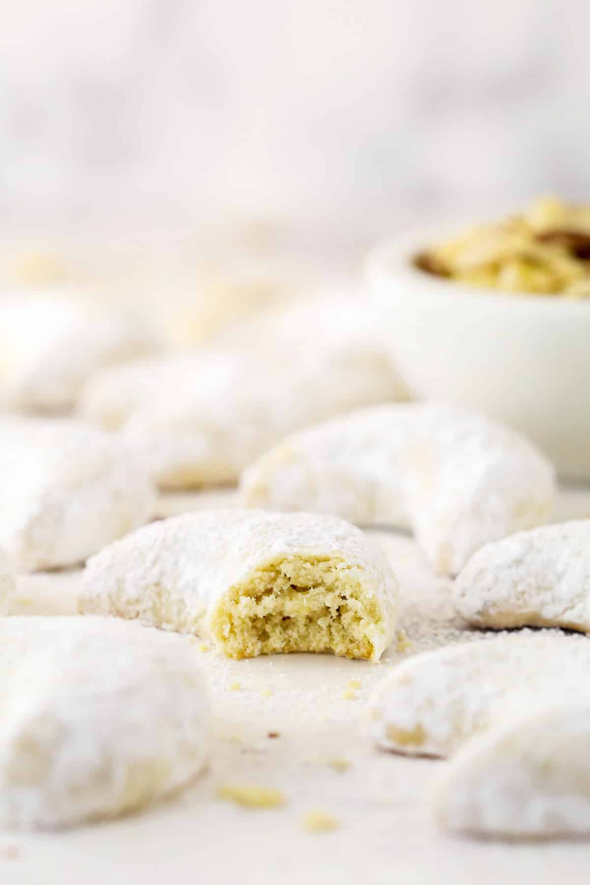 Close up of an almond crescent cookie with a bite missing.