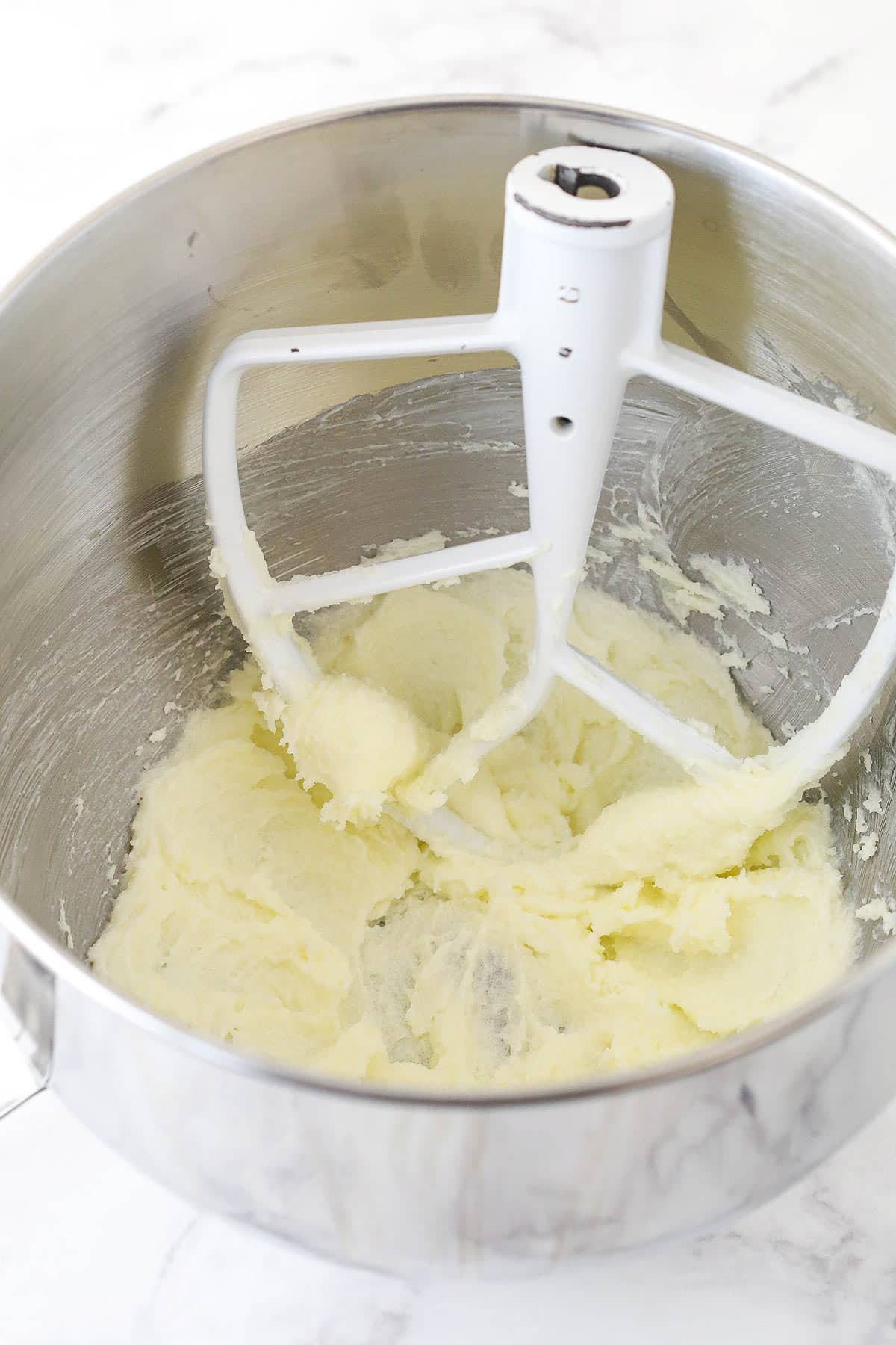 Creaming butter and sugar in a metal mixing bowl.