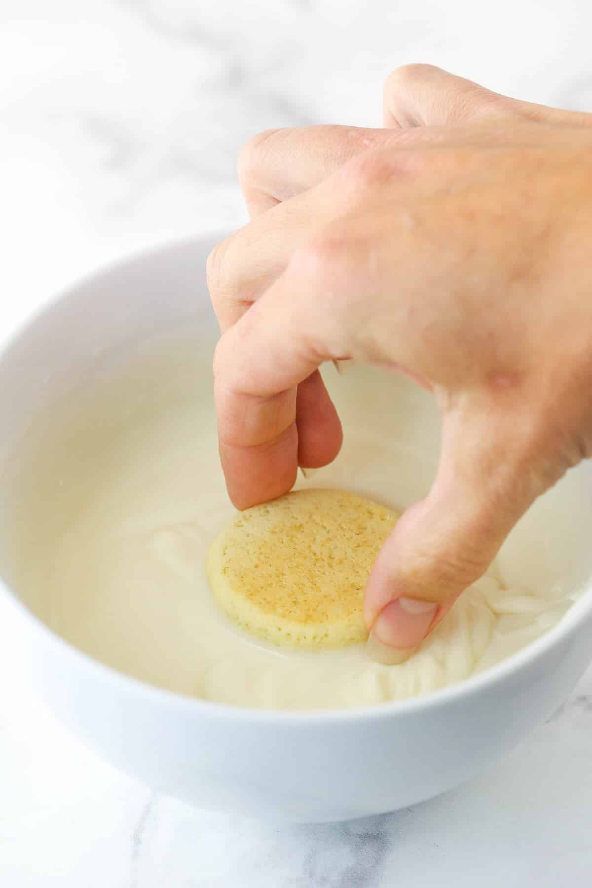 Dipping the tops of anise cookies into a bowl of icing.