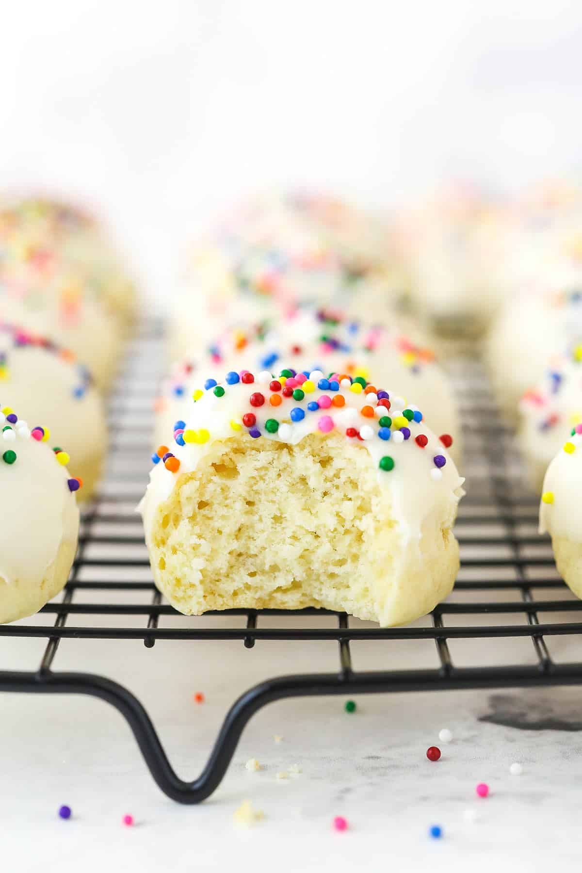 Festive Anise Cookies are soft, flavorful, and not too sweet. These Italian Cookies are a perfect addition to your Christmas gathering. An iced anise cookie with a bite missing.