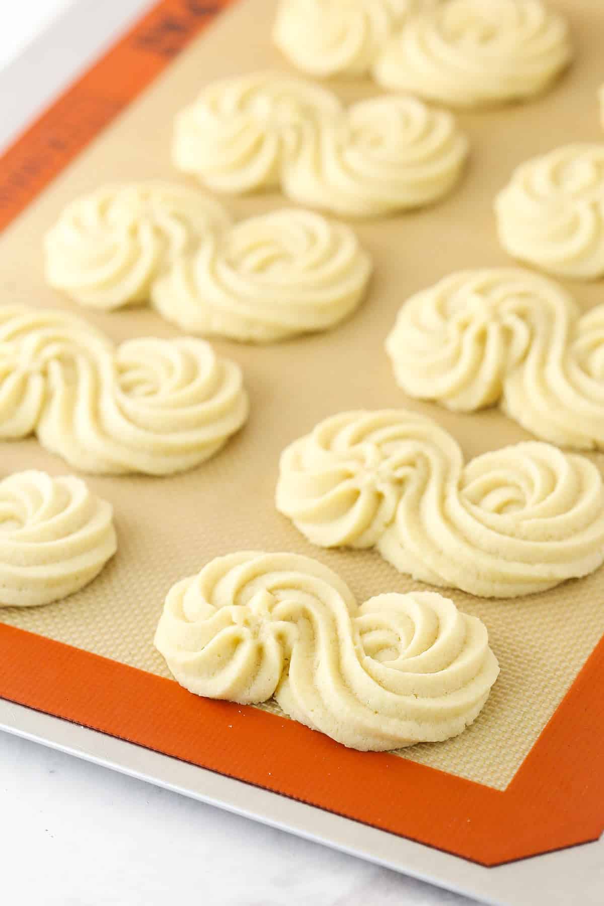 Cooked spritz cookies on a baking sheet.
