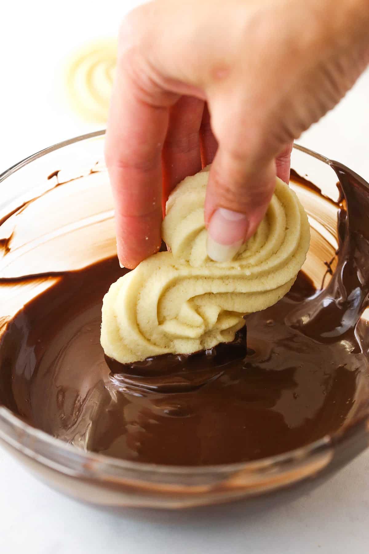 Dipping spritz cookies in melted chocolate