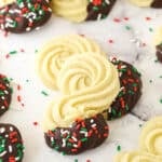 Spritz cookies dipped in chocolate and decorated with colorful sprinkles