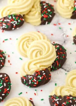 Spritz cookies dipped in chocolate and decorated with colorful sprinkles