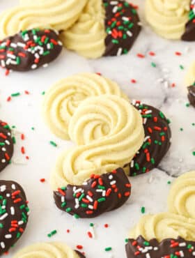 Spritz cookies dipped in chocolate and decorated with colorful sprinkles